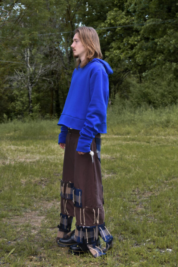 Applicazioni rettangolari in due tipologia di tessuto ( nylon marrone e cover di lana fantasia a quadri) applicate tramite corde dal ginocchio in giu in forma obliqua. Parte piu lunga all'esterno parte piu corta interna.